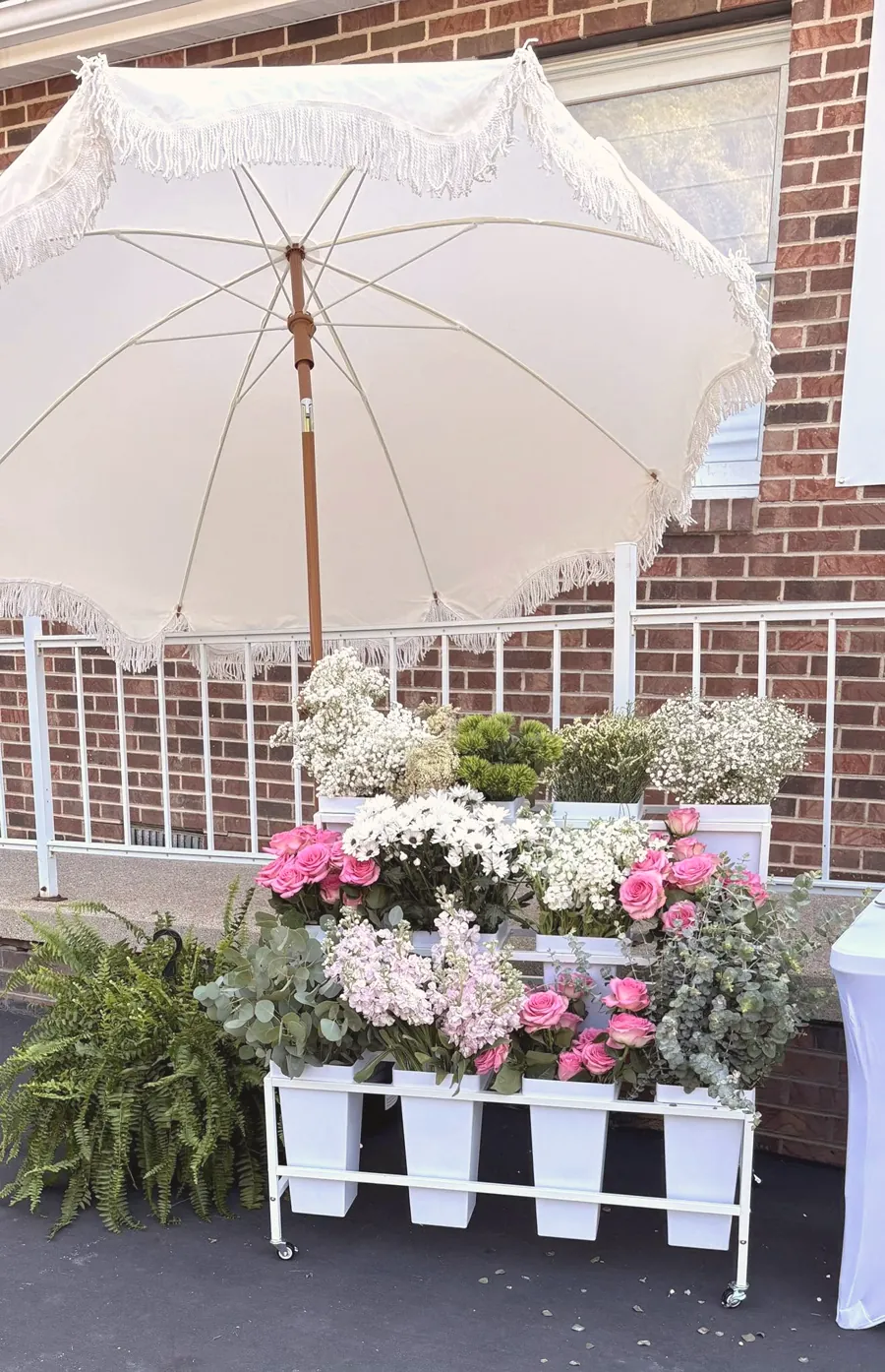The Lillie Blooms flower cart full of fresh blooms under a white fringed umbrella